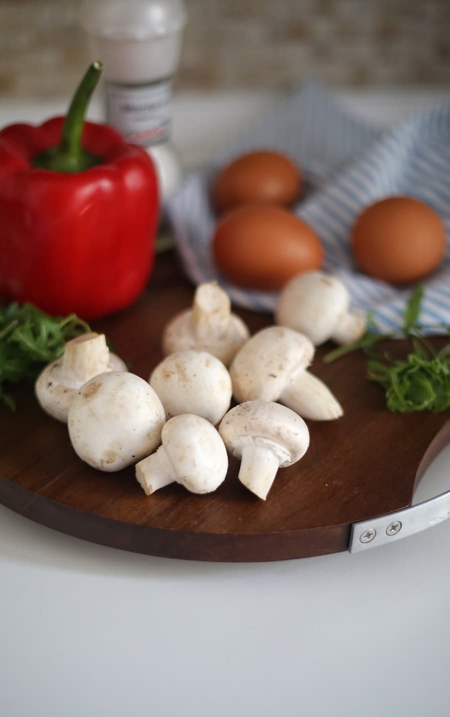 Champignons, poivron rouge, œufs et herbes posés sur une planche